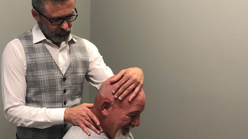 A chiropractor performing a hands-on neck and shoulder adjustment